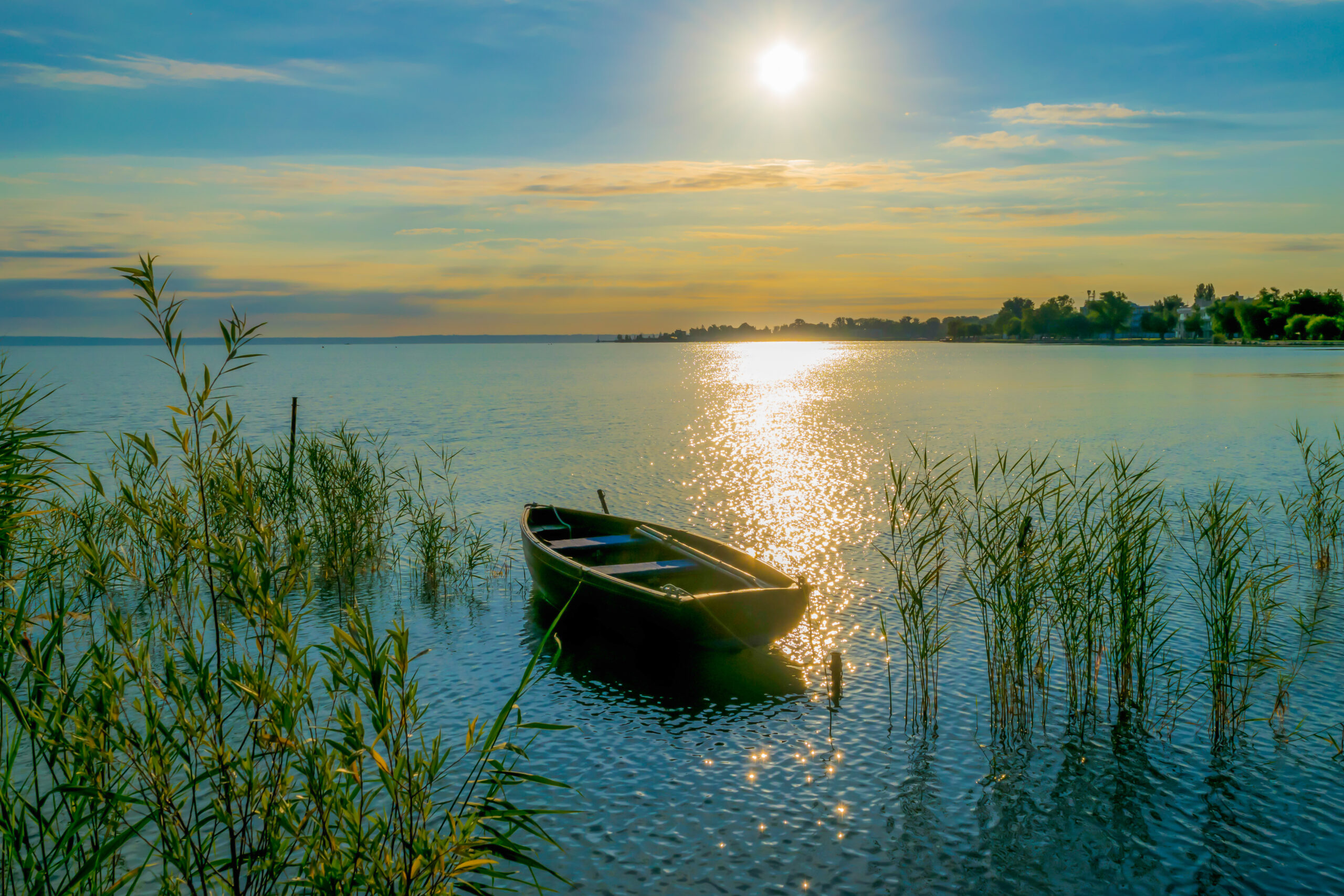 Rowing boat on lake at sunset. Small wooden rowing boat on a calm lake at sunset.